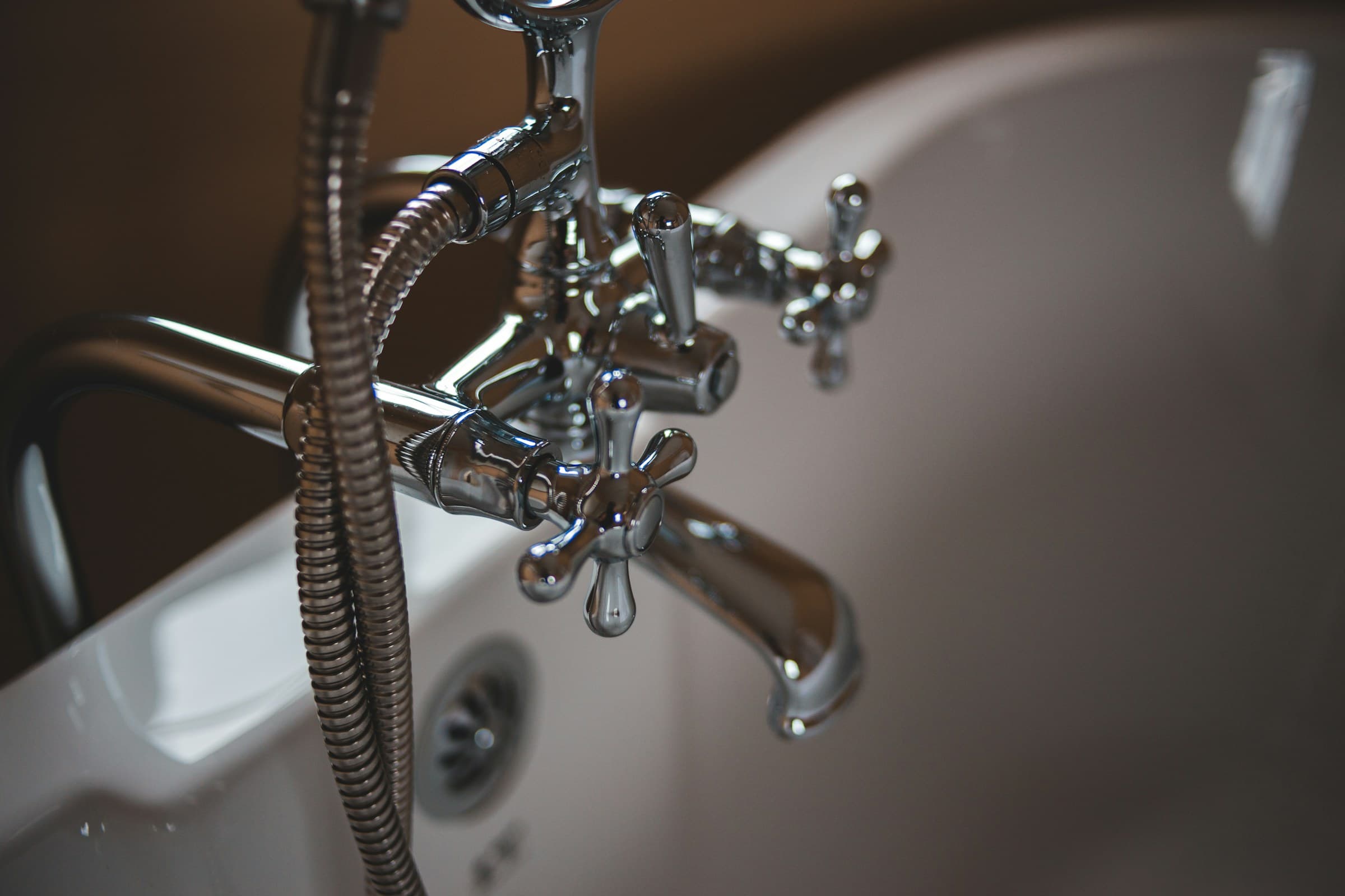 Chrome tub faucet and spout over a white bathtub