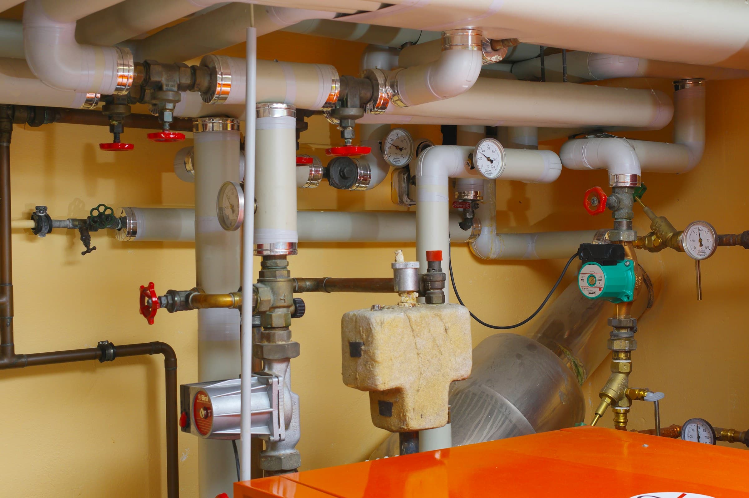 Water heater piping, valves and pressure gauges in a utility room